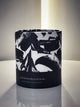 A photo of the artsy and iconic round tube packaging within which all postmodernform candles are packaged. The bottom half of the tube is black with the words 'postmodernform' and 'hand poured in san francisco' written. The top half is white with large artistic black paint strokes.